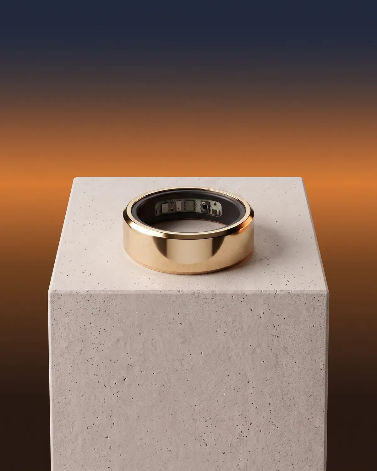 The Liwa ring in warm gold lying on a stone plinth, its sensors showing inside, against an amber sunset